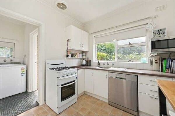 Spacious kitchen featuring white cabinets, large window, and essential appliances in Surrey Hills VIC.